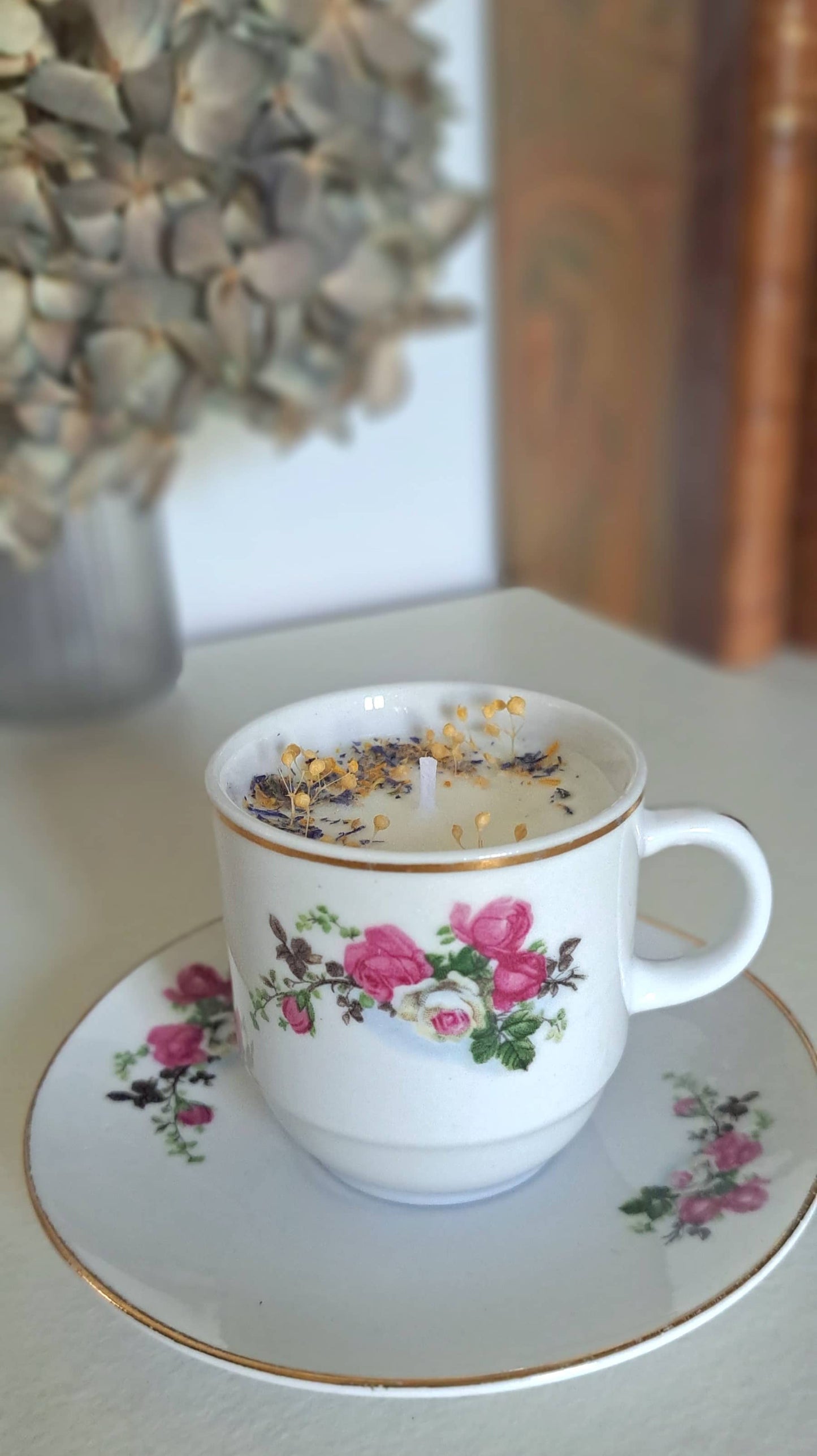 Bougie parfumée dans tasse ancienne avec des fleurs séchées