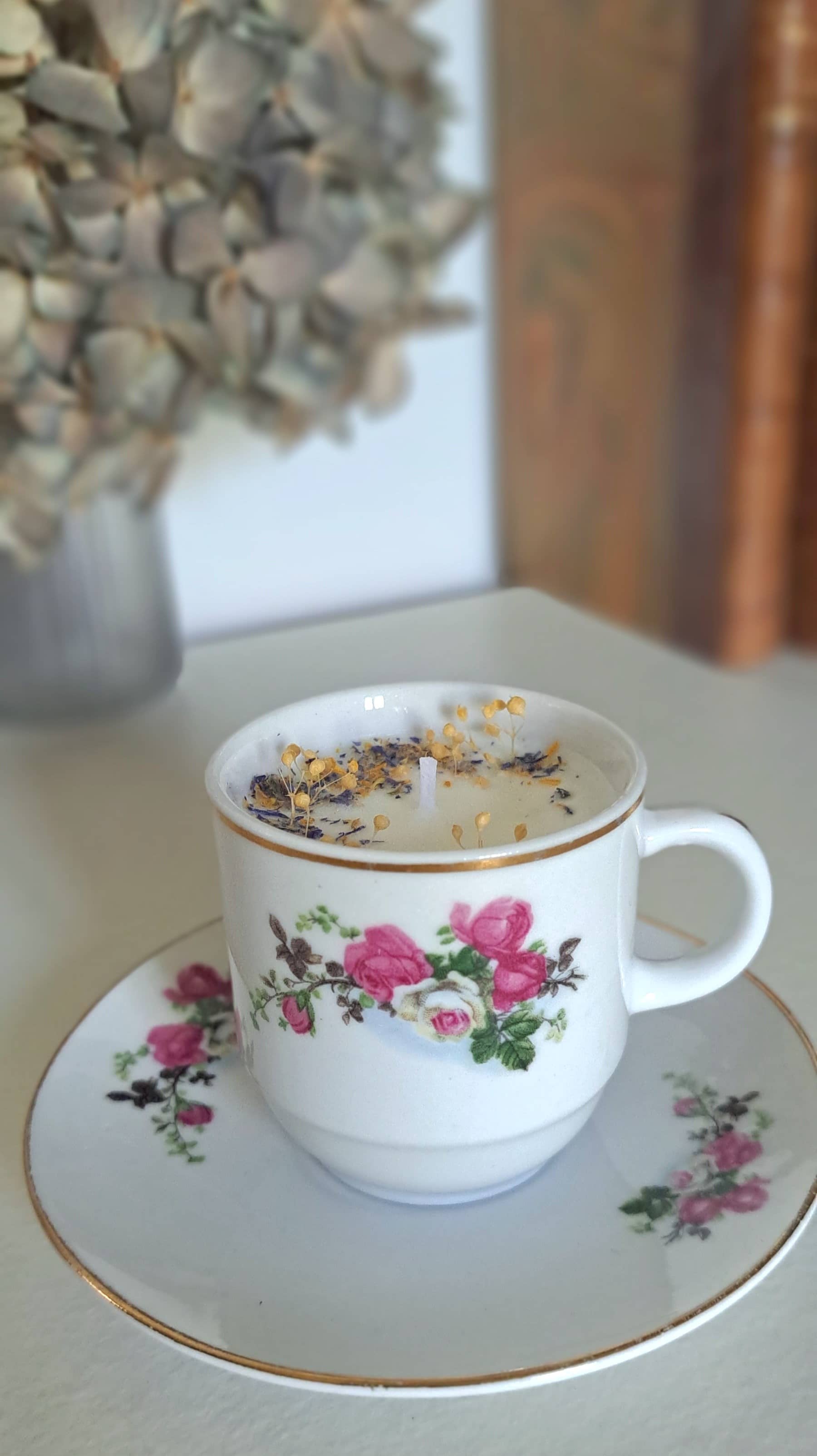 Bougie parfumée dans tasse ancienne avec des fleurs séchées